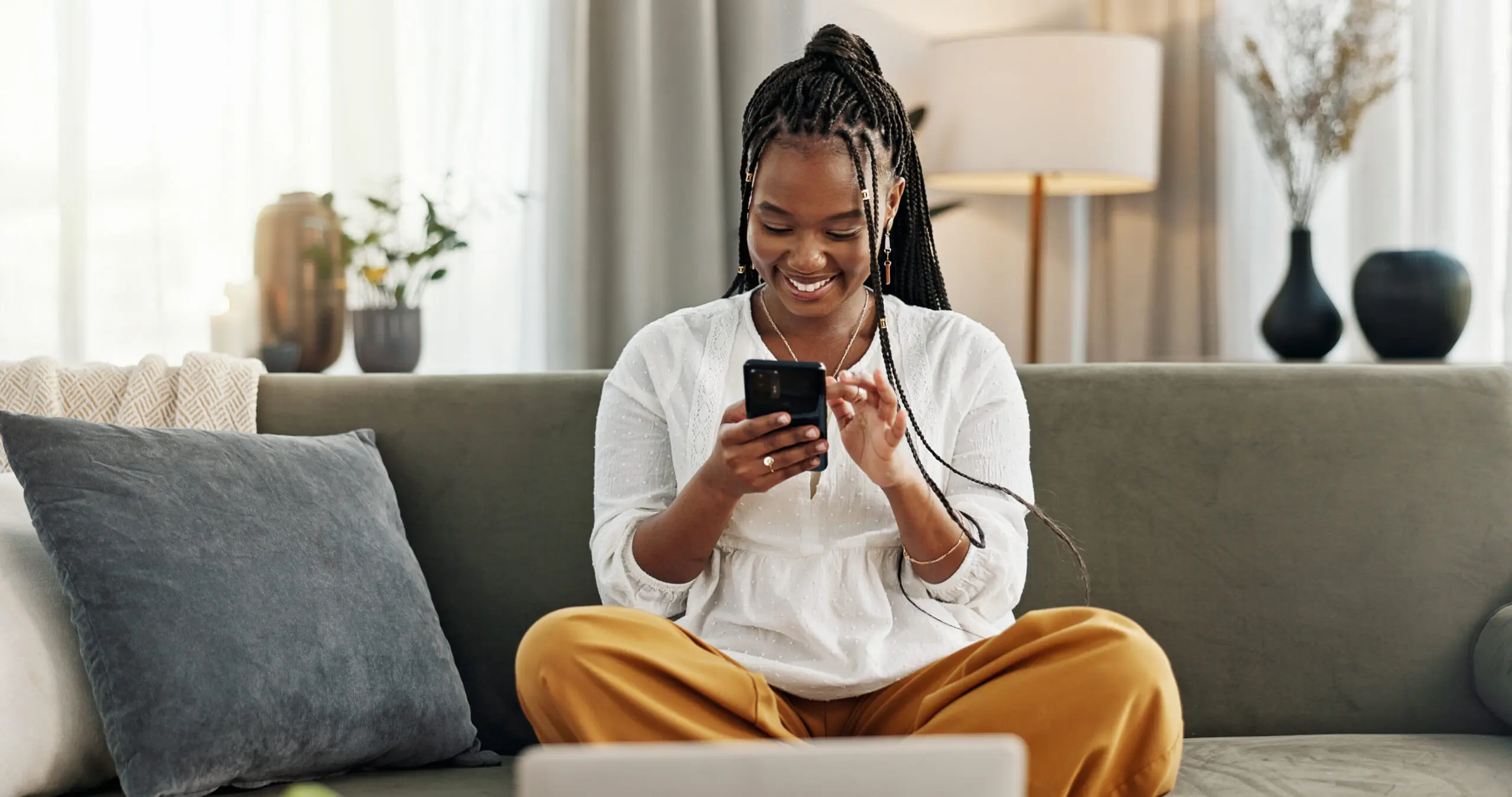 A woman sitting on the couch looking at her phone.