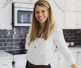 Kelly Rouse A woman standing in front of a kitchen sink.