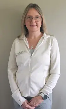 Rosey Hooton A woman in white jacket standing next to wall.
