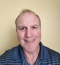 Tad Peloquin A man with a shaved head and a blue shirt