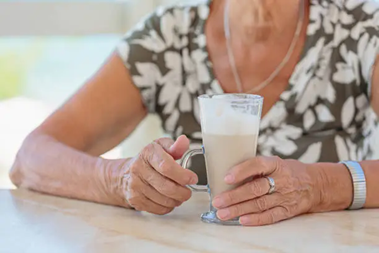 Waste Related Cost Reduction A woman holding a cup of coffee on top of a table.