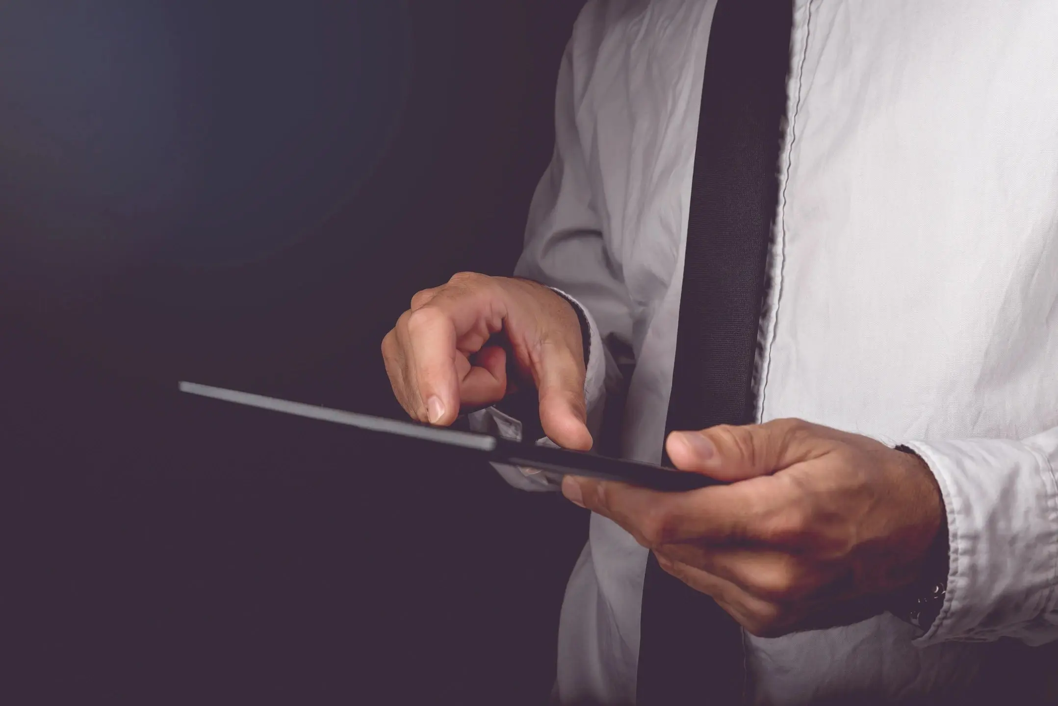 qtq80-YPMEIV A man in a white shirt and tie cutting something with scissors.