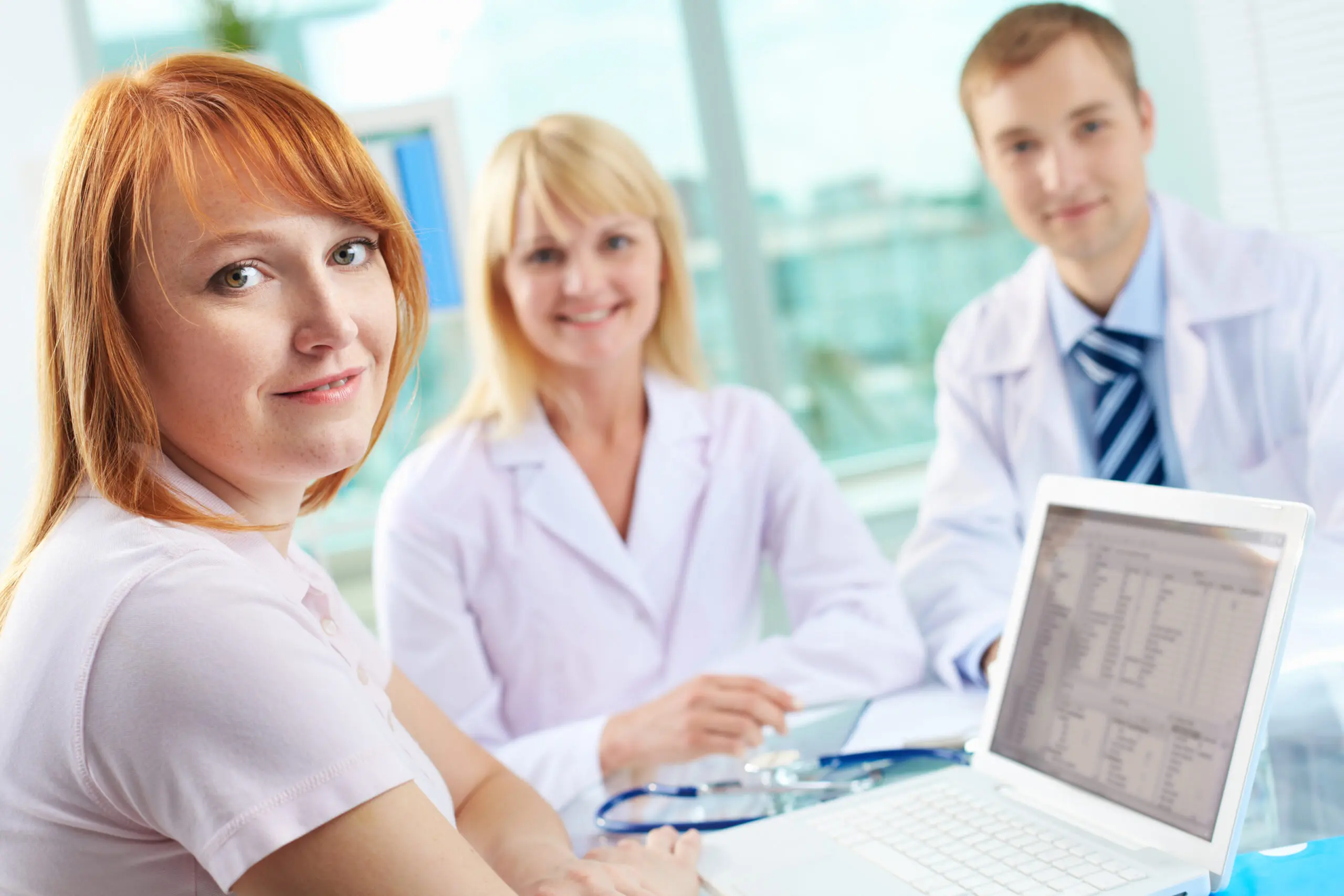 Patient in clinic Portrait of female patient looking at camera on background of two practitioners