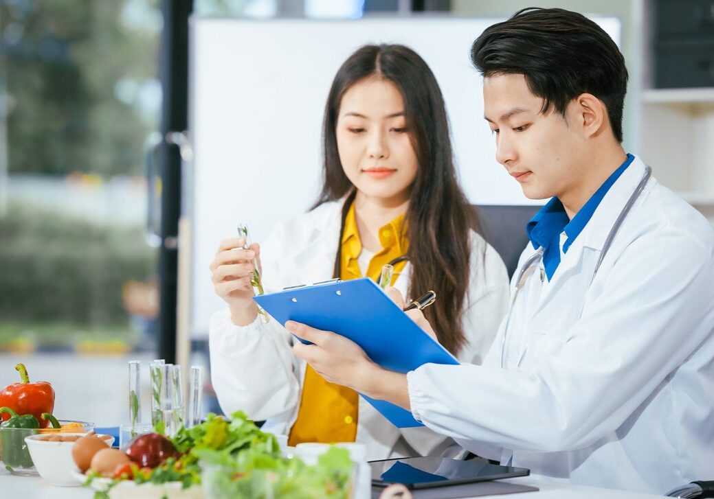 A man and woman in lab coats looking at a clipboard.